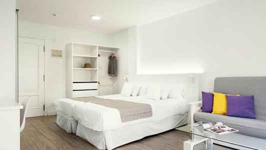 Ett ljust hotellrum med en dubbelsäng, en soffa och en garderob. (AI-genererad text)