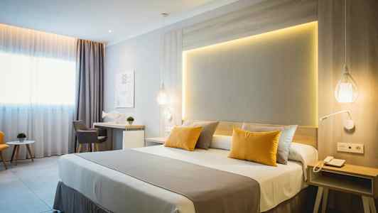 Ett modernt hotellrum med dubbelsäng, skrivbord och sittgrupp. (AI-genererad text)