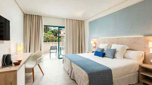Ett modernt hotellrum med en stor säng och öppet till en balkong. (AI-genererad text)