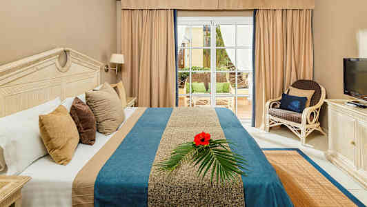 Bild av ett hotellrum med en säng, en TV, och utsikt mot en terrass. (AI-genererad text)