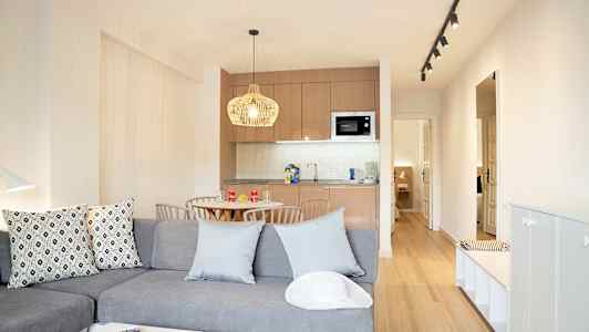 Modernt möblerat vardagsrum med köksdel och matbord. (AI-genererad text)