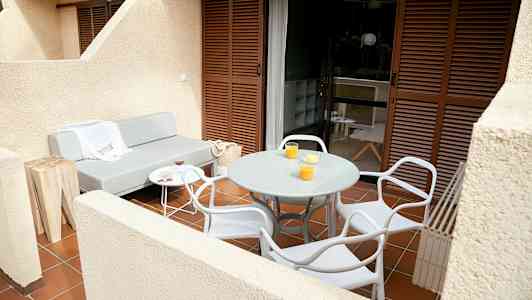 En terrass med en grå soffa, ett runt bord och stolar. (AI-genererad text)