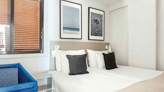 Ett hotellrum med en dubbelsäng, två kuddar och dekorationer på väggen. (AI-genererad text)