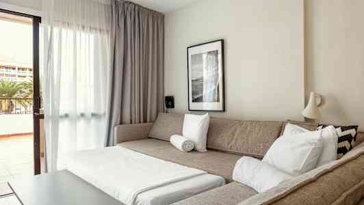 Ett vardagsrum med en bäddsoffa, ett soffbord och en utgång till balkongen. (AI-genererad text)