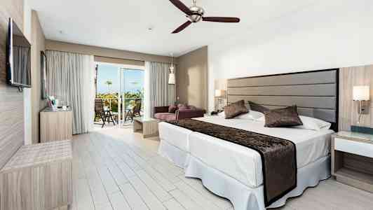 Modernt hotellrum med dubbelsäng, sittgrupp och balkong. (AI-genererad text)