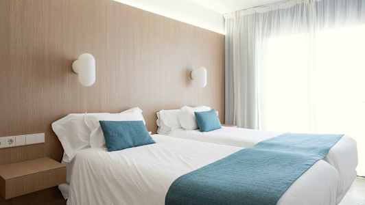 Rum med två enkelsängar och mjuka blå detaljer. (AI-genererad text)