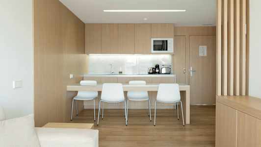 Ett modernt kök med träskåp, sittplats och vit utrustning. (AI-genererad text)