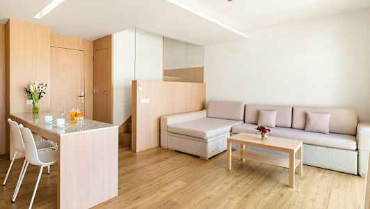 Ett modernt vardagsrum med trädetaljer, en soffa, ett soffbord och en matplats med stolar. (AI-genererad text)