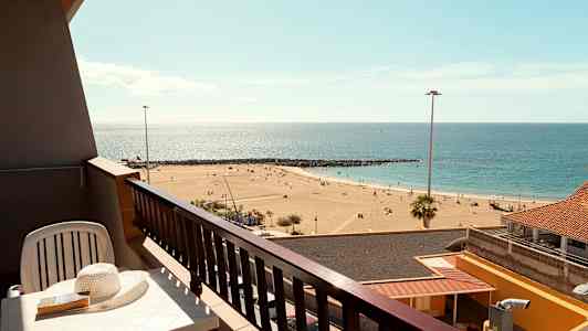 En balkong med utsikt över en sandstrand och havet. (AI-genererad text)