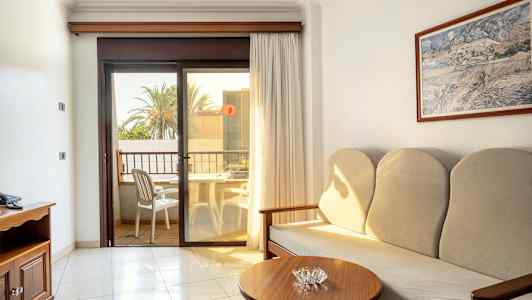 Ett hotellrum med soffa, sidobord och en balkong med utsikt. (AI-genererad text)