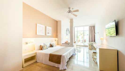 Ljust hotellrum med dubbelsäng och utsikt mot en terrass. (AI-genererad text)