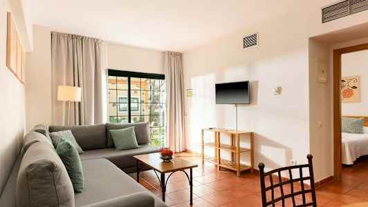 Bild av ett vardagsrum med en grå soffa, bord och en TV upphängd på väggen. (AI-genererad text)