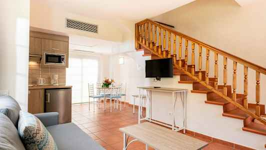 Ett vardagsrum med trapp, köksutrustning och matplats. (AI-genererad text)