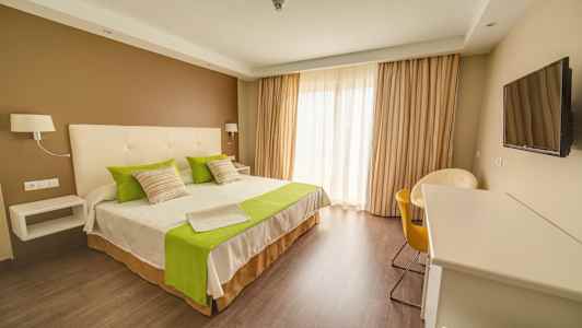 Hotellrum med dubbelsäng, gröndetaljer och modern inredning. (AI-genererad text)