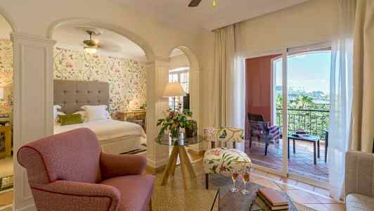 Ett hotellrum med en sittgrupp, säng och balkong. (AI-genererad text)