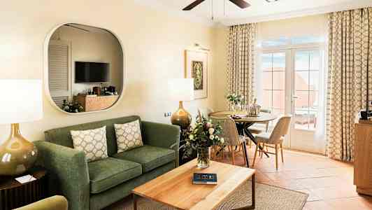 Ett vardagsrum med soffa, soffbord, matsalsplats och glasdörrar som leder till en terrass. (AI-genererad text)