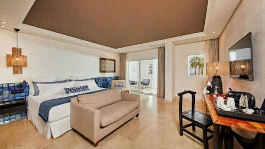 Hotellrum med dubbelsäng, soffa, skrivbord, TV och balkong. (AI-genererad text)