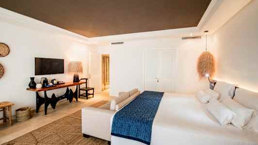 Ett modernt hotellrum med en stor säng och en sittgrupp, samt en TV och ett bord med kaffebryggare. (AI-genererad text)