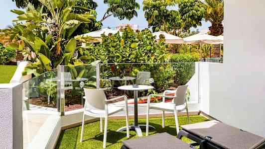 Trädgårdsterrass med grönska, utemöbler och solsängar. (AI-genererad text)