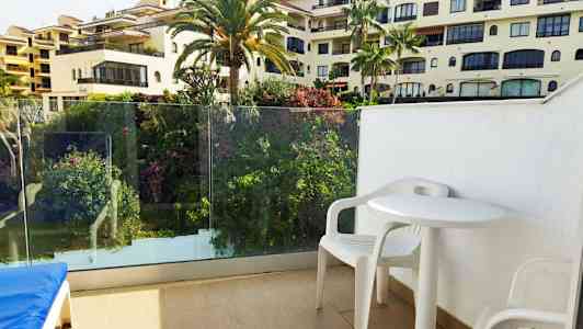 Utsikt från balkong med vita plastmöbler och omgivande grönska. (AI-genererad text)