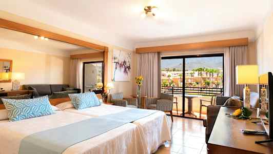 Ett hotellrum med två sängar, sittgrupp och balkong med utsikt. (AI-genererad text)