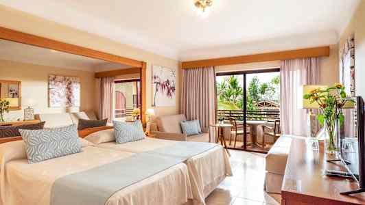 Hotellrum med två sängar, en sittgrupp och en balkong. (AI-genererad text)