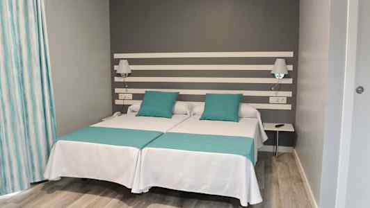 Dubbelrum med två enkelsängar och grå vägg. (AI-genererad text)