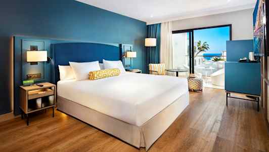 Hotellrum med dubbelbädd, sittmöbler och utsikt mot havet. (AI-genererad text)