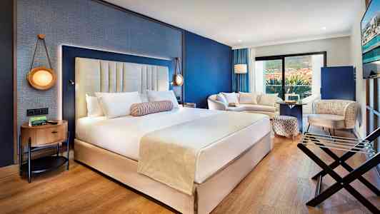 Ett modernt hotellrum med en stor dubbelsäng, sittgrupp och balkong. (AI-genererad text)