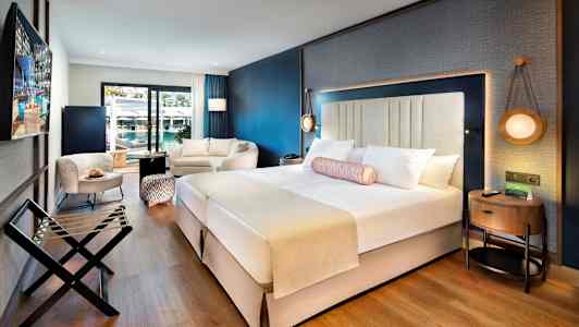 Modernt hotellrum med dubbelsäng, sittgrupp och balkong. (AI-genererad text)