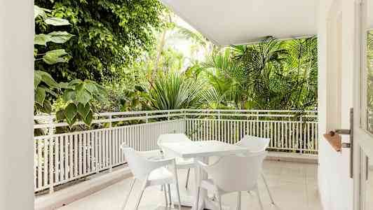 Terrass med vita trädgårdsmöbler och omgiven av grönska. (AI-genererad text)