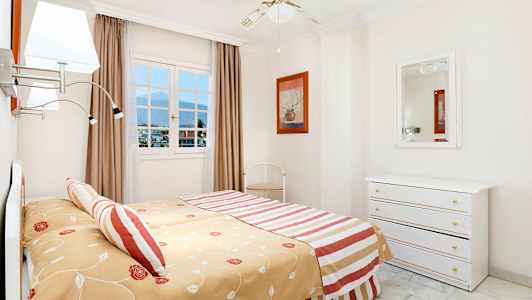 Ett sovrum med en stor säng, en spegel och ett fönster med utsikt. (AI-genererad text)