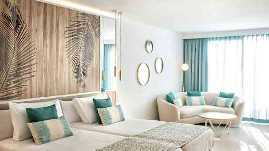 Ett modernt hotellrum med två enkelsängar, sittgrupp och dekorationer. (AI-genererad text)