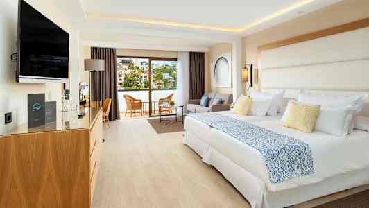 Ett hotellrum med två sängar, sittgrupp och balkong. (AI-genererad text)