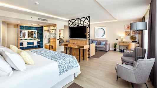 Ett hotellrum med en stor säng, sittgrupp och skrivbord. (AI-genererad text)