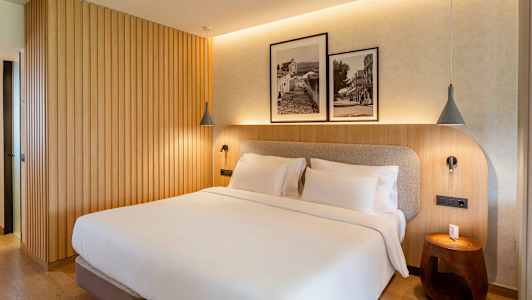 Ett sovrum med en dubbelsäng, träpanelvägg och två inramade svartvita fotografier ovanför sängen. (AI-genererad text)