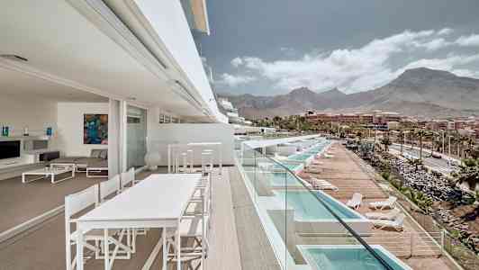 En terrass med utsikt över pooler och berg i bakgrunden. (AI-genererad text)