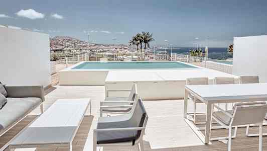 Terrass med möbler, utsikt över poolen och havet i bakgrunden. (AI-genererad text)