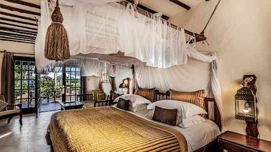 Ett sovrum med genomtänkt inredning, dubbelsäng med himmelssäng och utgång till terrass. (AI-genererad text)