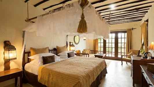 Ett sovrum med en stor bädd, myggnät och traditionella möbler. Fönster med utsikt. (AI-genererad text)