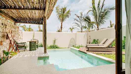 Terrass med liten pool, solstolar och växtlighet under ett träpergola. (AI-genererad text)