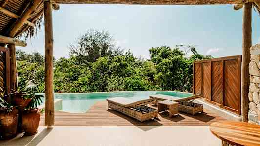 En infinitypool med trädeck och solstolar i en tropisk omgivning. (AI-genererad text)