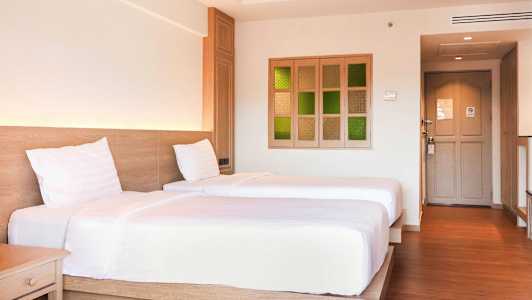 Två enkelsängar i ett hotellrum med trägolv och ljust inredd inredning. (AI-genererad text)