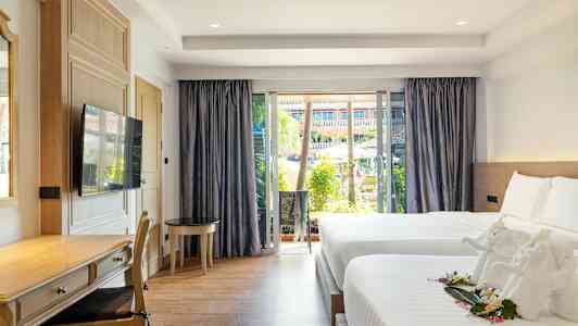 Ett hotellrum med två sängar, en skrivbordshörna och ett stort fönster med utsikt över en pool och trädgård. (AI-genererad text)