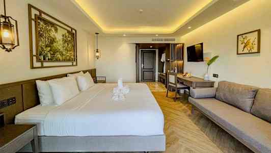 Modernt inrett hotellrum med dubbelsäng, soffa och arbetsyta. (AI-genererad text)