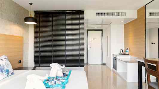 Hotellrum med säng, dekorerad med handdukar formade som elefanter, och en arbetsyta. (AI-genererad text)