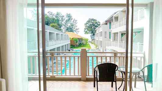 Utsikt från balkong mot poolområde och hotellbyggnader. (AI-genererad text)