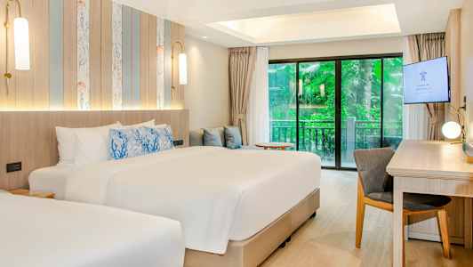 Ett modernt hotellrum med två sängar, skrivbord och skjutdörrar mot en grönskande utsikt. (AI-genererad text)