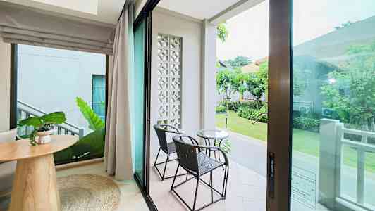 Utsikt från ett rum med glasdörrar till en uteplats med två stolar och ett bord. (AI-genererad text)