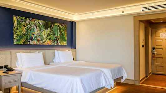 Hotellrum med två sängar och en färgglad tavla på väggen. (AI-genererad text)